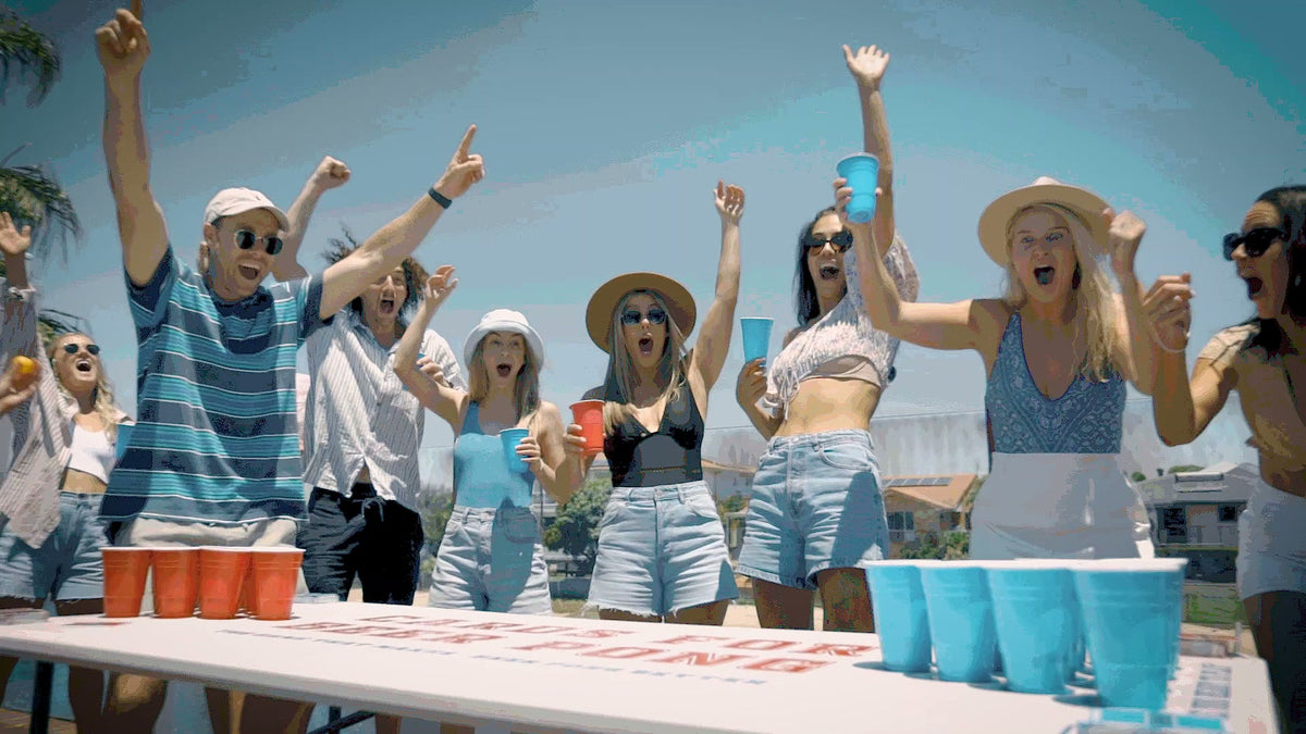 Friends cheering around a Cards For Beer Pong game in the backyard